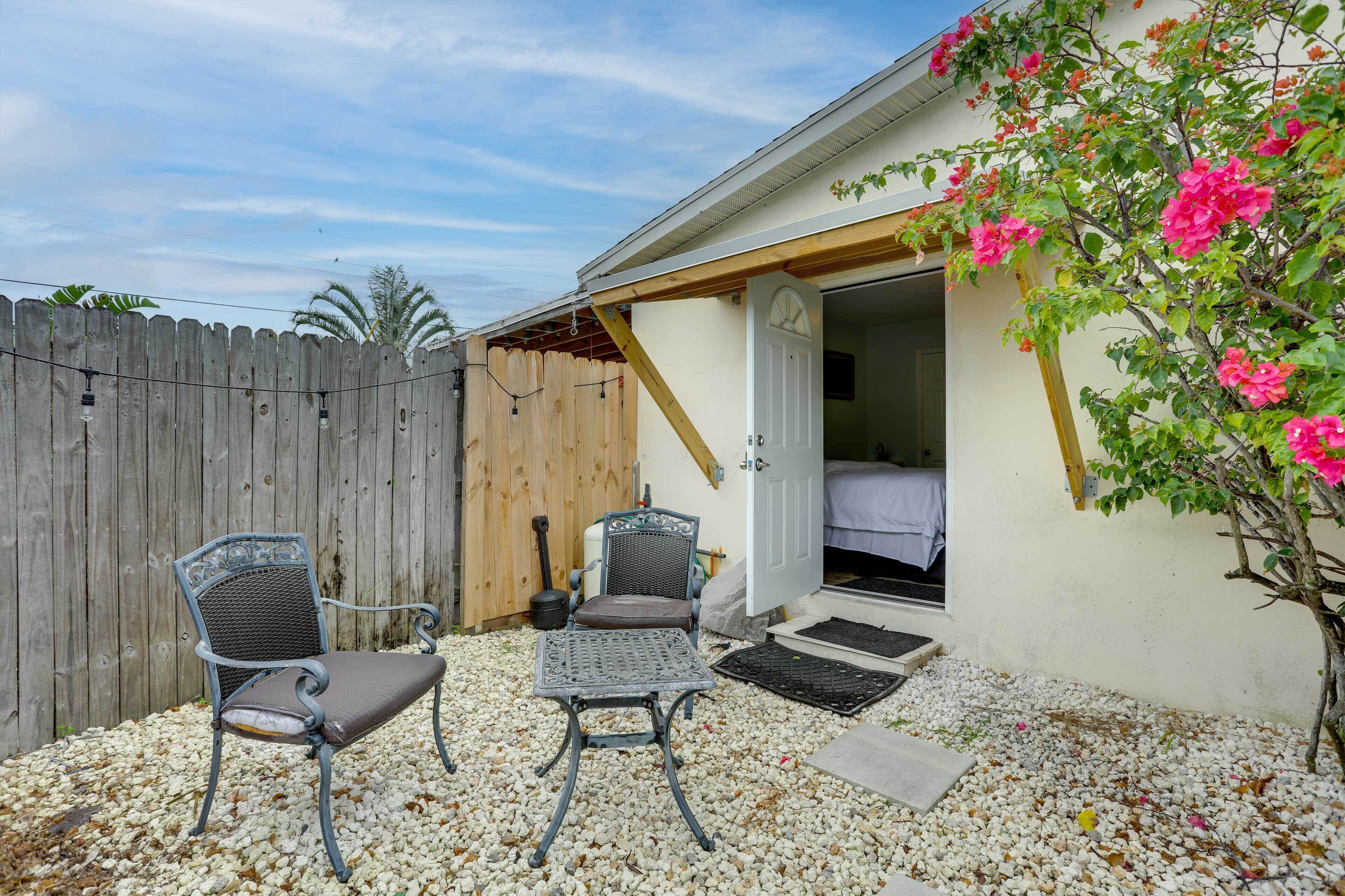 A patio with two metal chairs, a wooden fence, and a house with a white door.