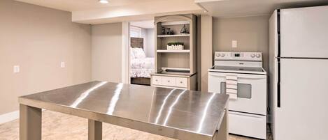 A compact kitchen with a stainless steel table, a built-in oven, and a refrigerator.