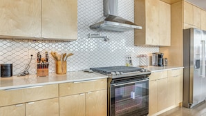 A modern kitchen with wooden cabinets, a stainless steel range hood, and a built-in oven. - Families Welcome: Phoenix Home w/ Backyard Oasis (Phoenix)