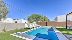 A rectangular swimming pool with a clear blue water surface, surrounded by a well-maintained lawn and a low brick wall. - Families Welcome: Phoenix Home w/ Backyard Oasis (Phoenix)