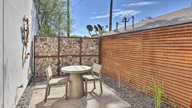 A patio with a round table and two chairs, a metal fence, and a corrugated metal wall. - Families Welcome: Phoenix Home w/ Backyard Oasis (Phoenix)
