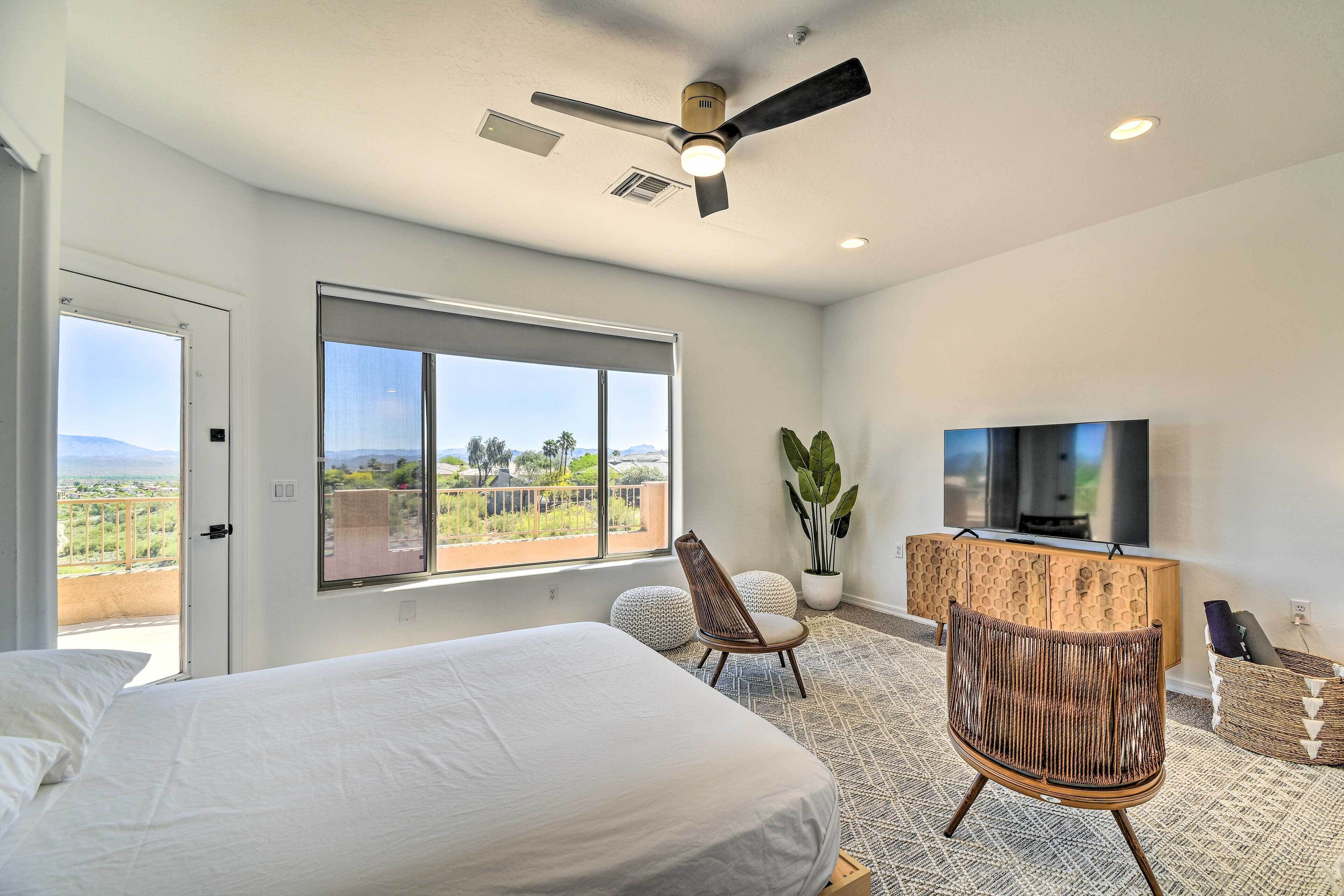 Une chambre moderne avec un grand lit, un ventilateur de plafond, une télévision et un balcon avec vue.