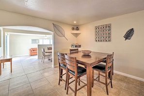 A dining area with a wooden table and chairs, a decorative leaf wall art, and a patterned wall hanging. - 3 Mi to Lake Havasu: Home w/ Patio (Lake Havasu City)
