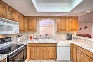 Una cucina con mobili in legno, un forno a microonde, un piano cottura, una lavastoviglie e un lavello.