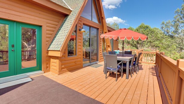 A wooden cabin with a deck, a dining area with outdoor furniture, and a red umbrella. - Hot Tub & Mtn View: Dog-friendly Payson Getaway! (Payson)