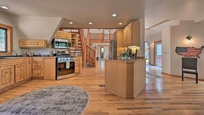 A spacious kitchen with wooden cabinets, a central island, and a staircase leading to an upper level. - Hot Tub & Mtn View: Dog-friendly Payson Getaway! (Payson)