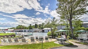 Une terrasse au bord de l’eau, dotée de chaises longues et de tables, un quai avec des bateaux, et un bâtiment portant l’inscription « THUPE MARINE ».