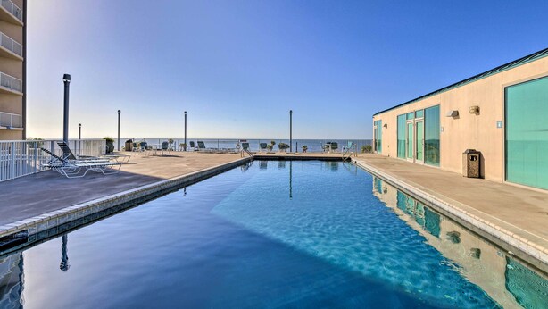 A swimming pool with lounge chairs and a building with large windows. - Spacious Biloxi Getaway w/ Pools & Beach Access! (Biloxi)