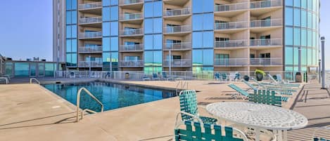 A modern hotel with a pool area, outdoor seating, and a large building with multiple balconies.