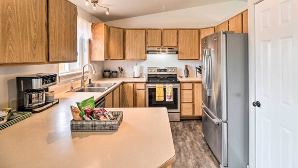 A modern kitchen with wooden cabinets, stainless steel appliances, and a central island. - New! Kalispell House w/ Grill < 35 Mi to Glacier! (Kalispell)