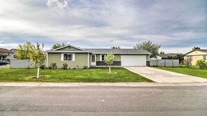 A single-story house with a front garage, a small front yard with a young tree, and a driveway leading to the garage. - New! Kalispell House w/ Grill < 35 Mi to Glacier! (Kalispell)