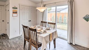 A dining area with a table set for four, a chandelier, and a view of the backyard through a sliding glass door. - New! Kalispell House w/ Grill < 35 Mi to Glacier! (Kalispell)