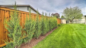 A backyard with a wooden fence, a well-maintained lawn, and a tree. - New! Kalispell House w/ Grill < 35 Mi to Glacier! (Kalispell)