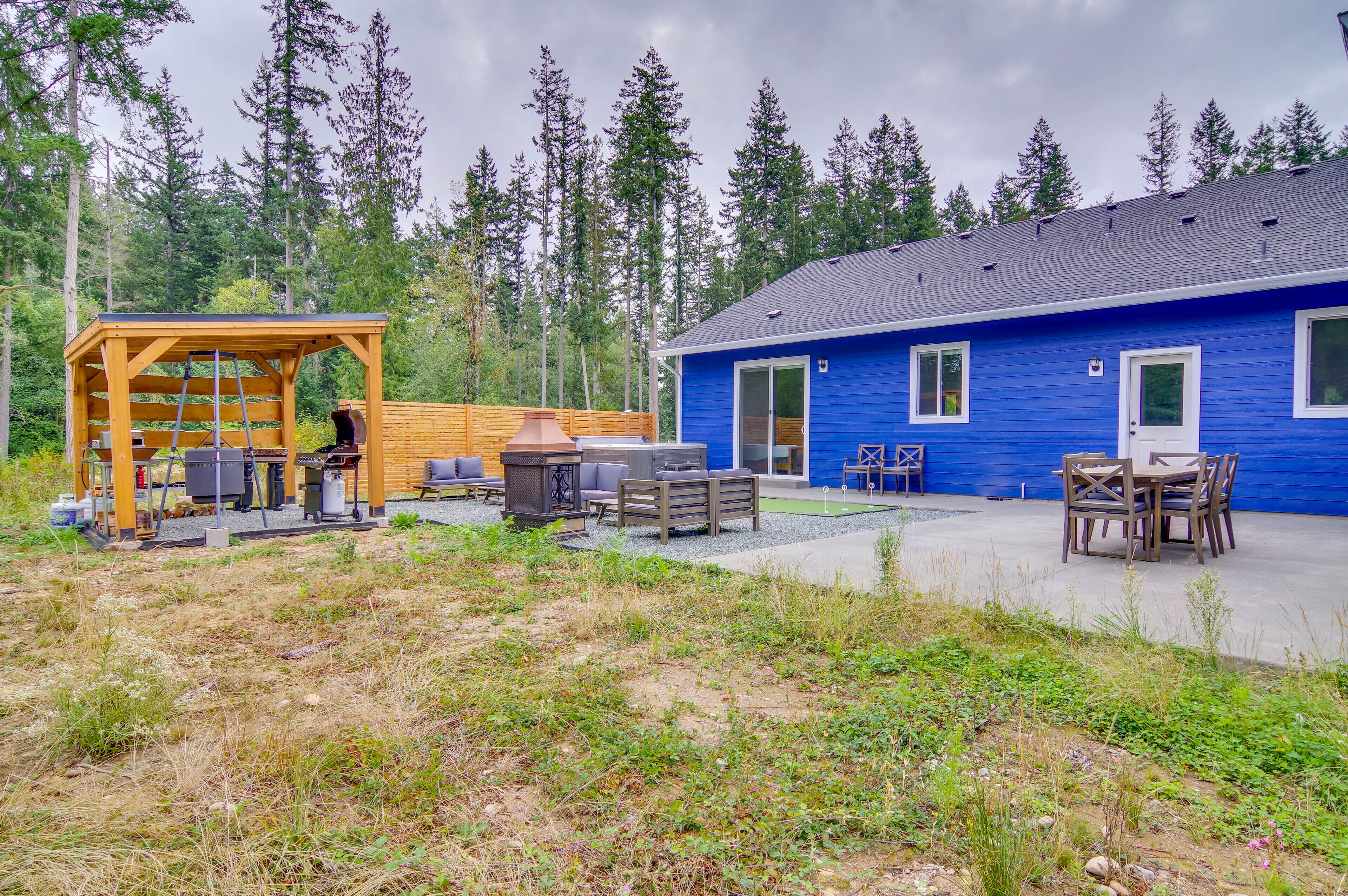 A blue building with a covered outdoor area, a patio, and a dining table with chairs.