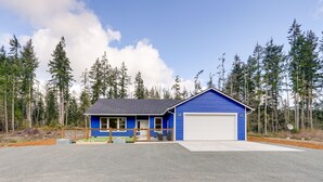Een blauw gebouw met een garage, omringd door een bos.