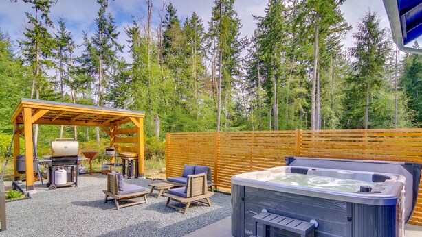 Een hottub, een terras en een barbecueplaats in een bebost gebied.