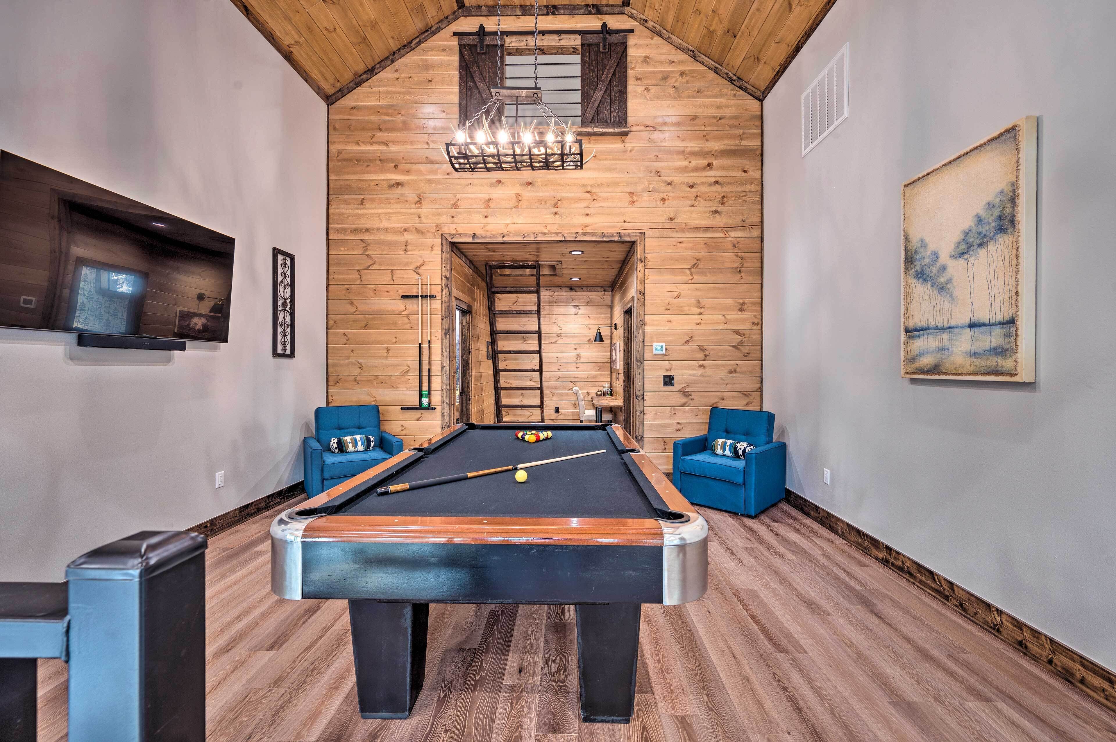 A pool table in a room with wooden walls and a sloped ceiling.