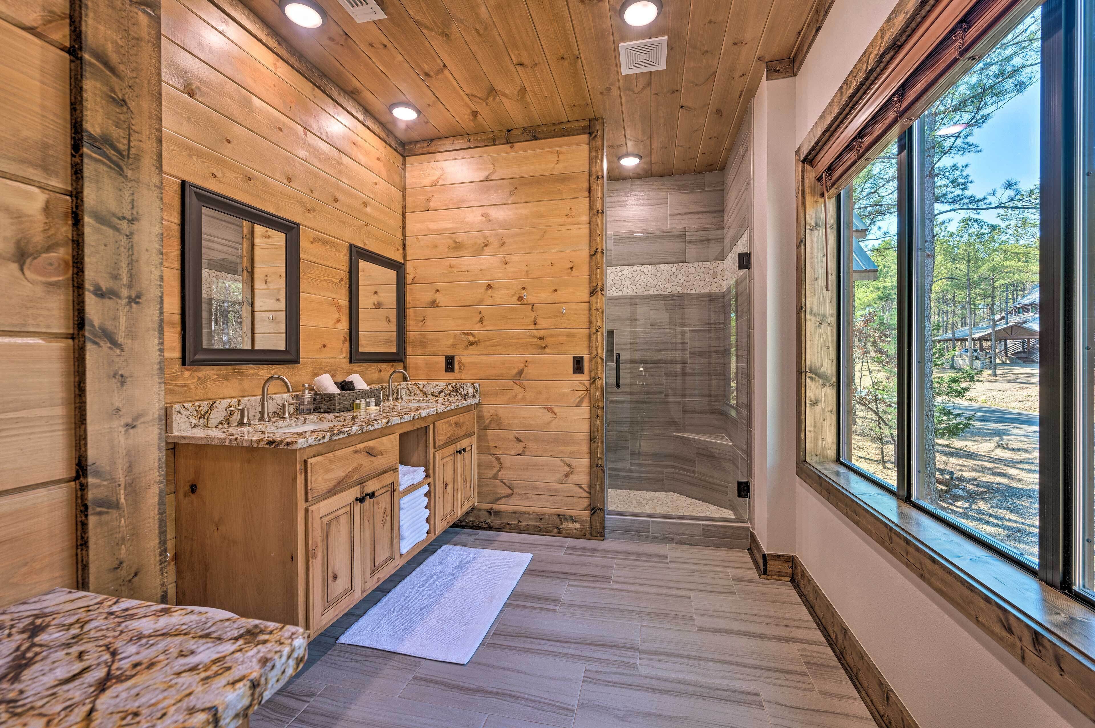 A wooden interior with a bathroom featuring a sink, mirrors, and a glass shower.