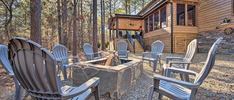 Una cabaña de madera con un hogar de piedra rodeado de sillas Adirondack.