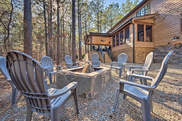 A wooden cabin with a stone fire pit surrounded by Adirondack chairs. - Broken Bow 'lazy Dog Lodge' w/ Hot Tub, Pool Table (Broken Bow)