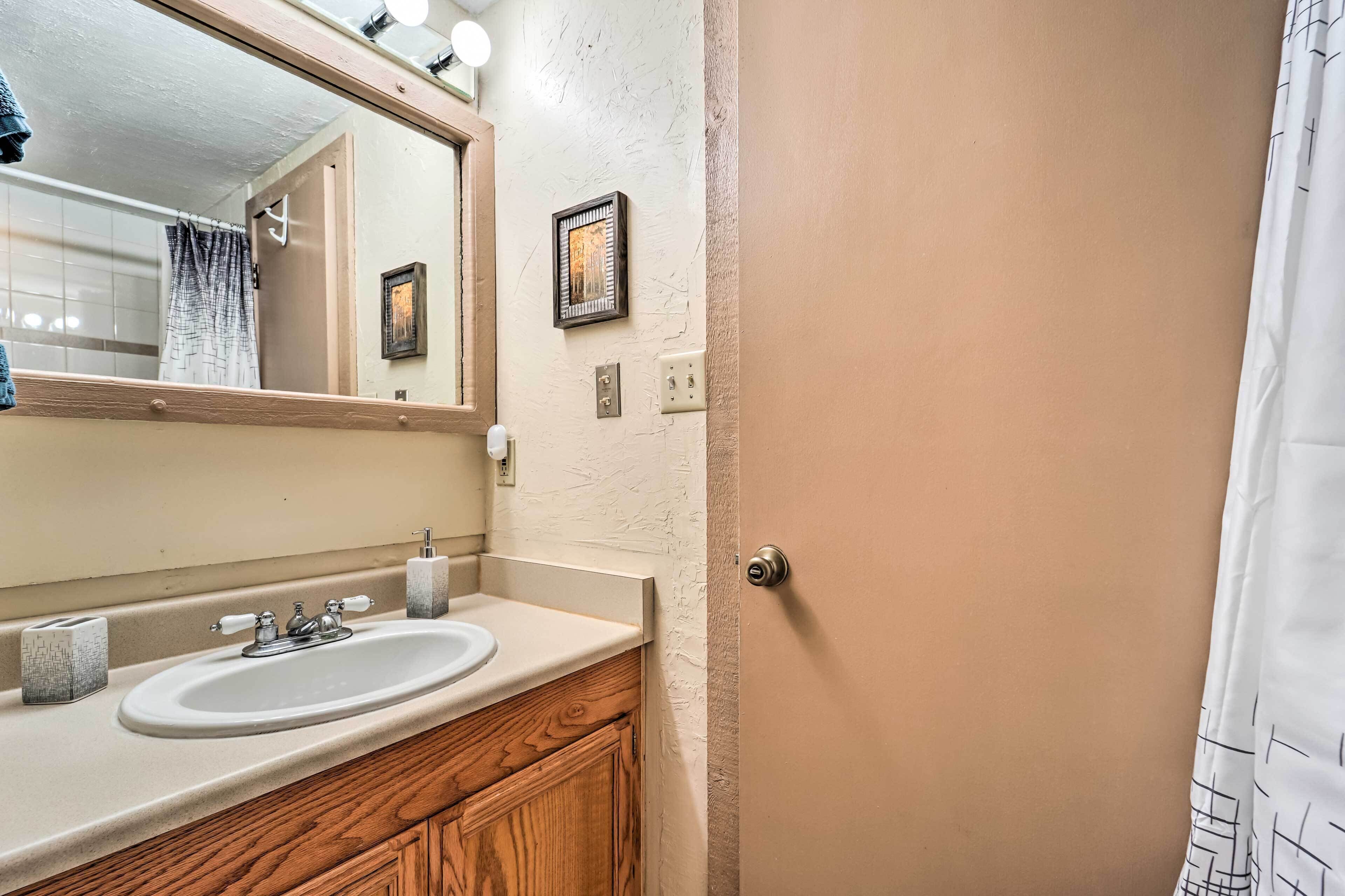 A bathroom with a white sink, wooden vanity, and a mirror above the sink.
