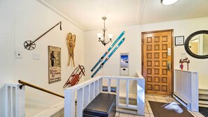 A hallway with a wooden door, a mirror, a bench, and ski-themed decorations including a welcome sign and a poster. - Slope Side Durango Condo at Purgatory Resort! (Durango)
