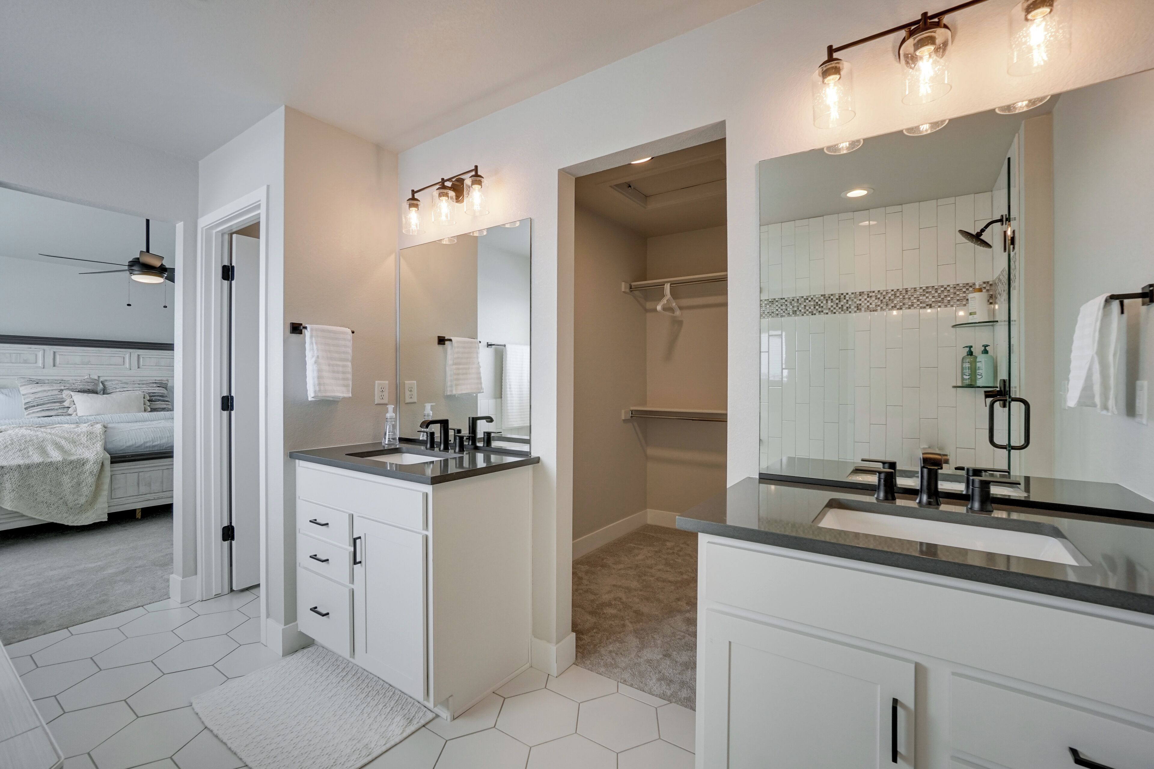 A modern bathroom with a large mirror, two sinks, and a shower area.