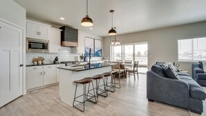 A modern kitchen with white cabinets, a central island with stools, and pendant lighting.