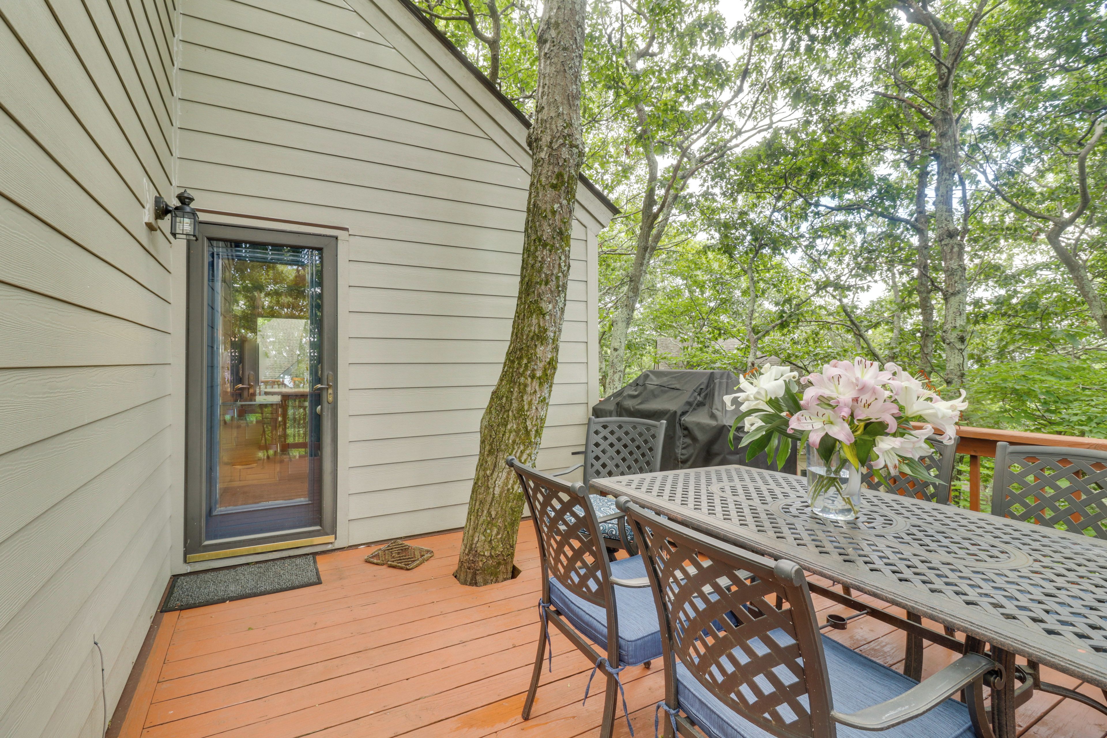 Une terrasse avec une table et des chaises, un barbecue et une porte donnant sur un espace intérieur.