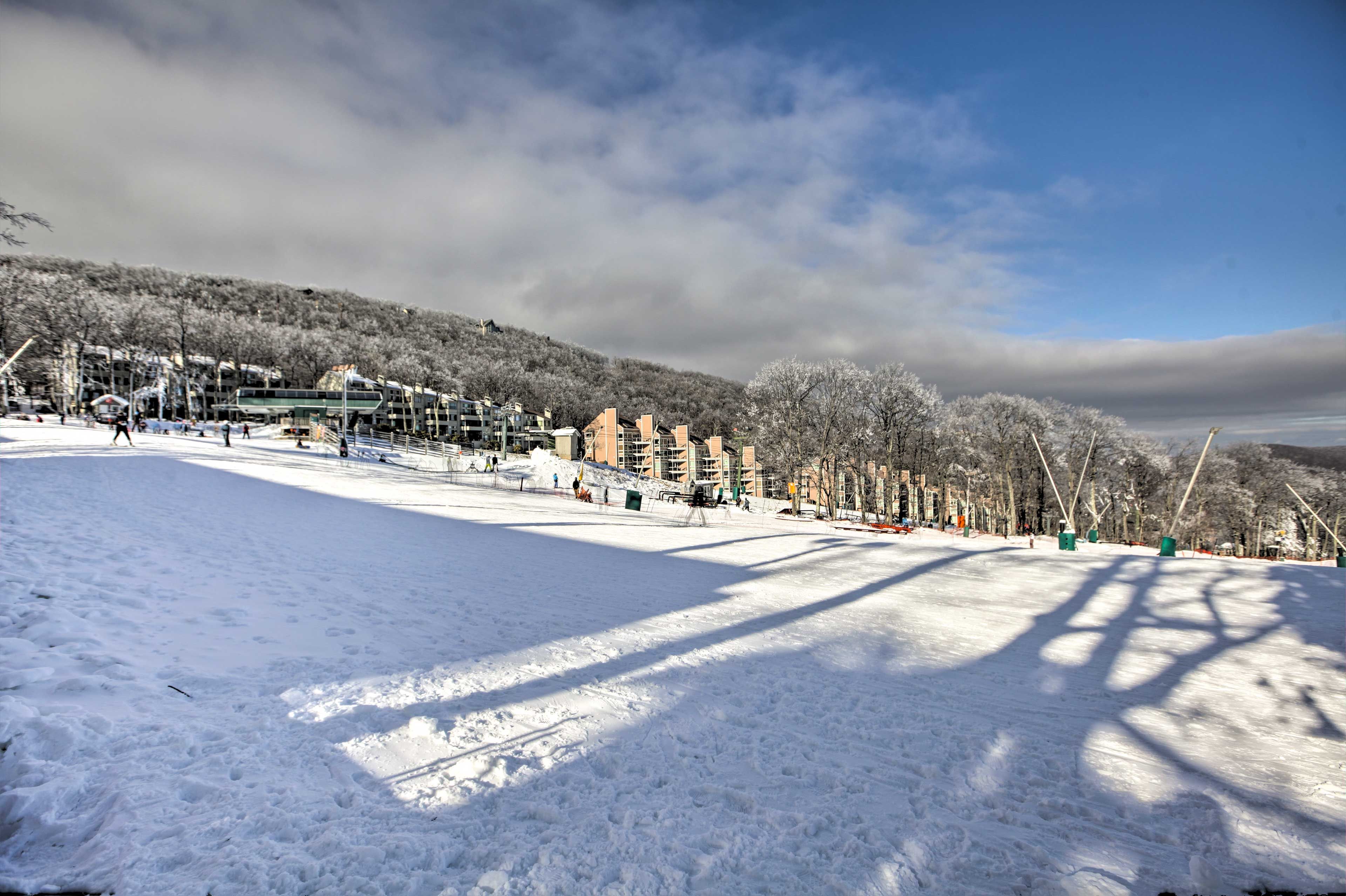 A snow-covered ski slope with buildings in the background.