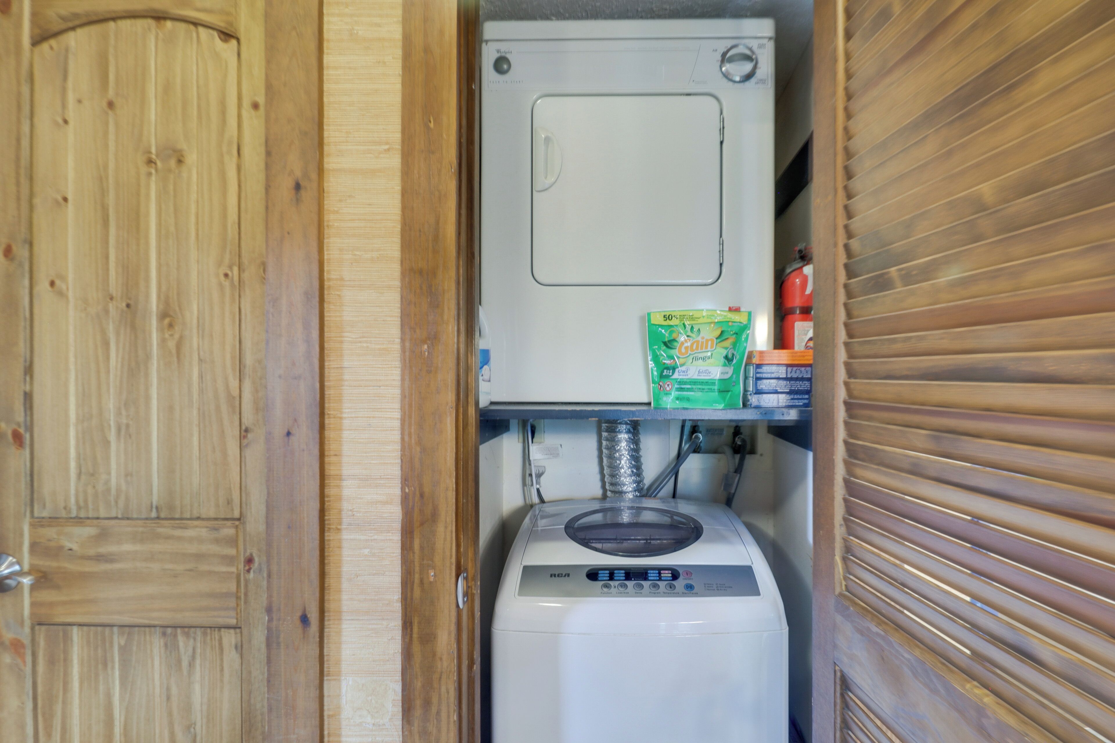 A compact kitchen with a microwave, a small refrigerator, and a shelf with a bag of Gain brand cereal.
