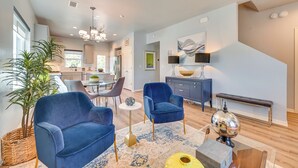 Ein geräumiges Wohnzimmer im modernen Stil, mit einem großen blauen Sofa, einem kleinen runden Tisch und einer dekorativen Lampe.