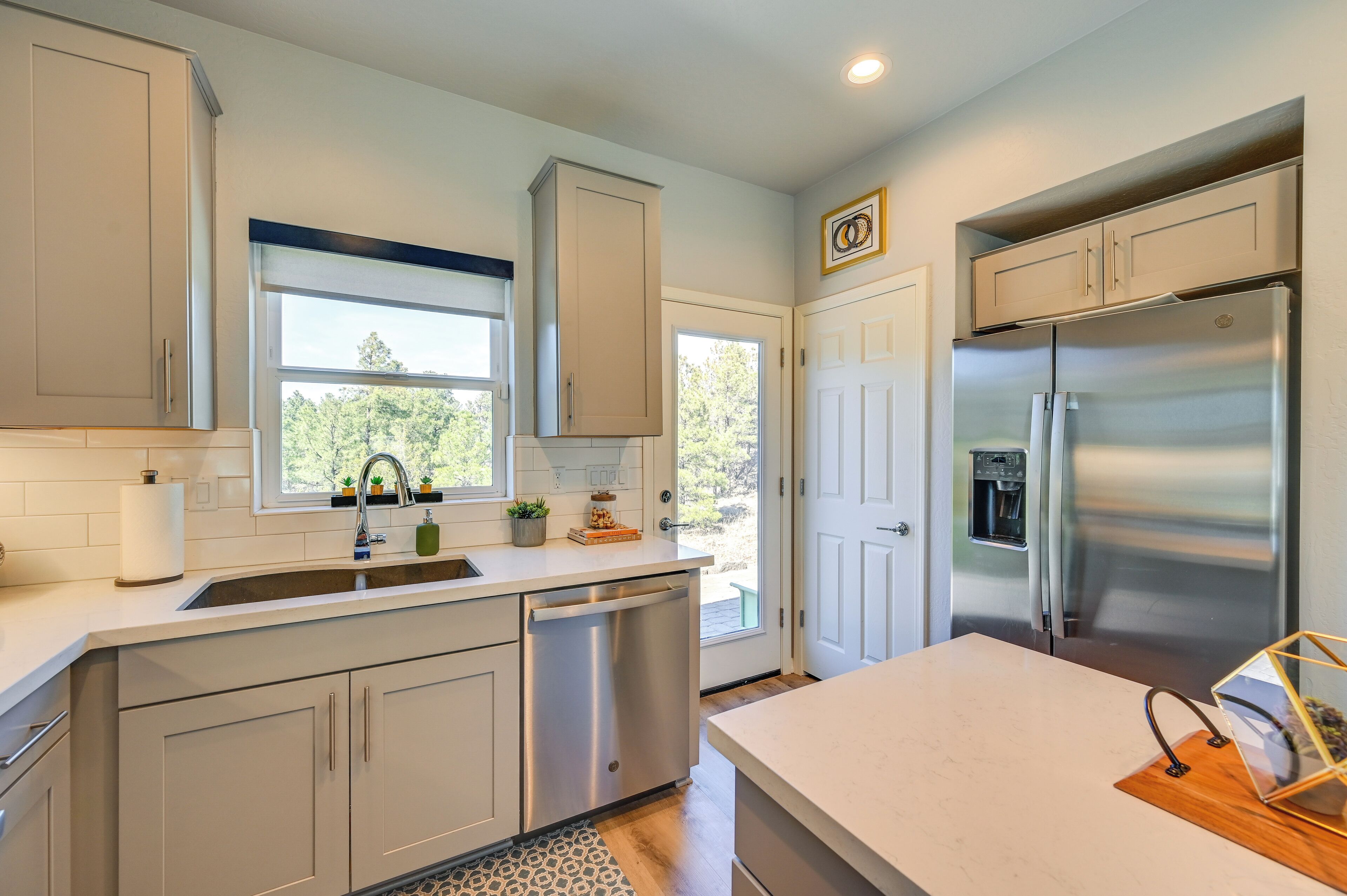 A modern kitchen with white cabinetry, a stainless steel refrigerator, and a built-in dishwasher.