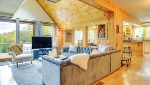 Un salon chaleureux avec un grand canapé gris, un téléviseur à écran plat et un plafond en bois.