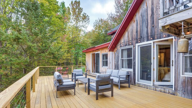 Une terrasse en bois avec des sièges extérieurs et de grandes fenêtres.