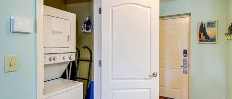 A laundry room with a washer and dryer, a blue towel rack, and a door leading to another room.