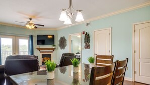 A dining area with a glass table, wooden chairs, a ceiling fan, and a fireplace. - Steps to Parkway! Pigeon Forge Condo + Pool Access (Pigeon Forge)