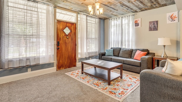 Un salon avec un plafond en bois, un canapé, une table basse et un tapis.