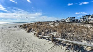 Une plage avec une clôture en bois et des maisons en arrière-plan.