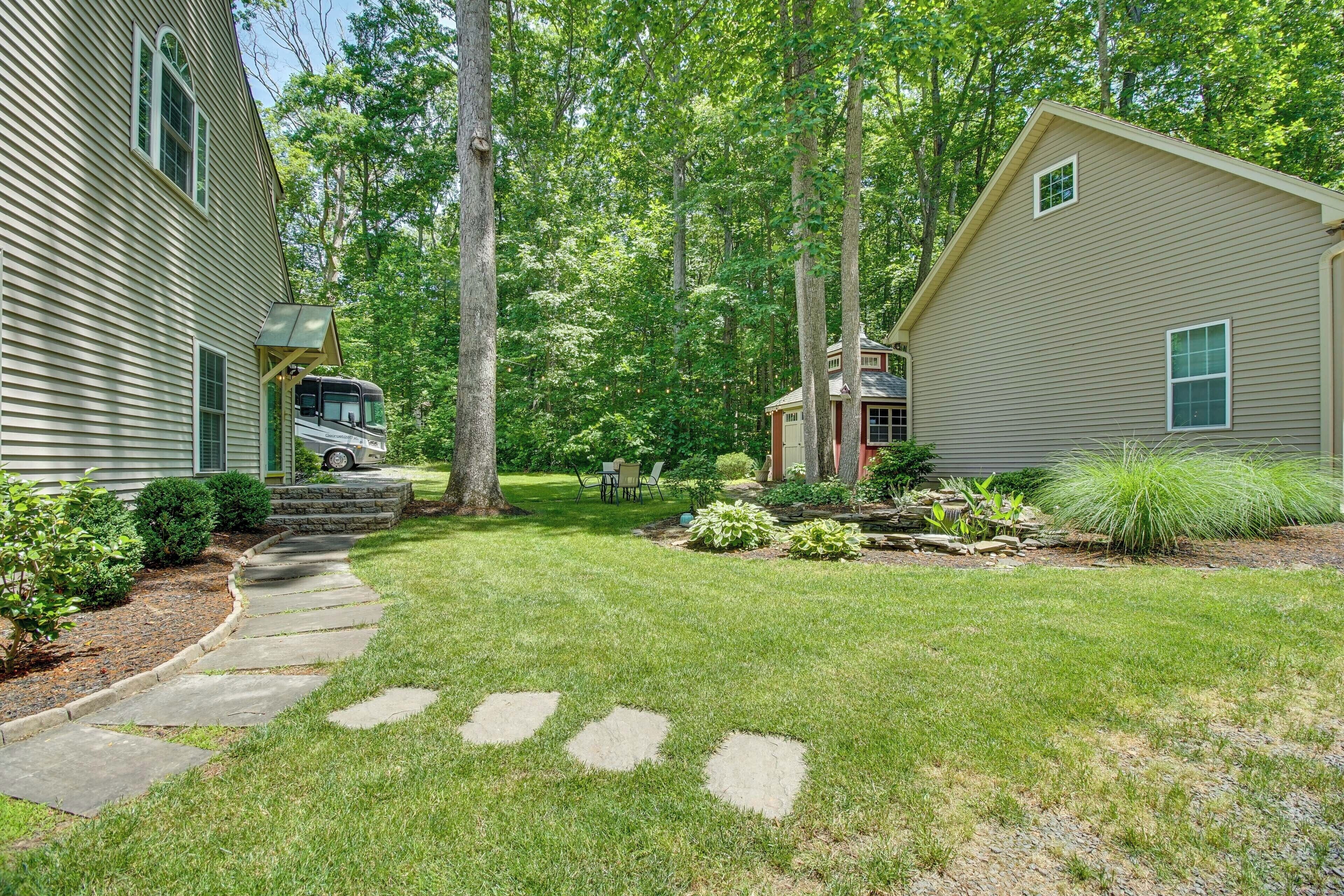 A residential property with a well-maintained lawn, stone pathway, and a small garden area with various plants.