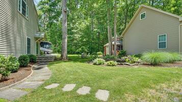 A residential property with a well-maintained lawn, stone pathway, and a small garden area with various plants.