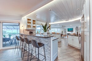 A modern kitchen with a central island, bar stools, and a view to the outdoors. - Upscale Naples Outdoor Getaway ~ 4 Miles to Beach (Naples)