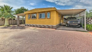 Et etplanshus med garage under tag, grusvej og et palmetræ.