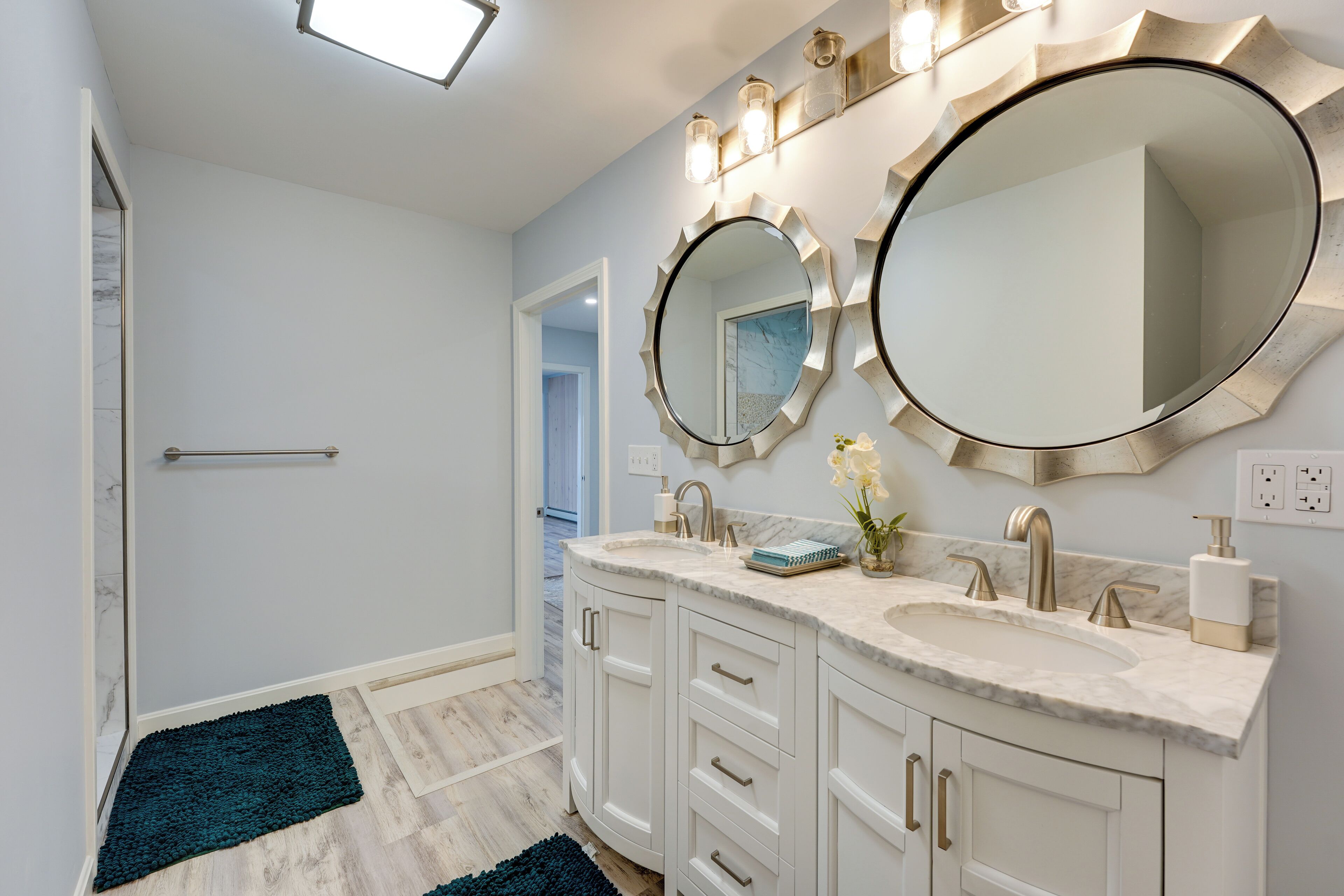 A bathroom with two sinks, a large mirror, and a shower.