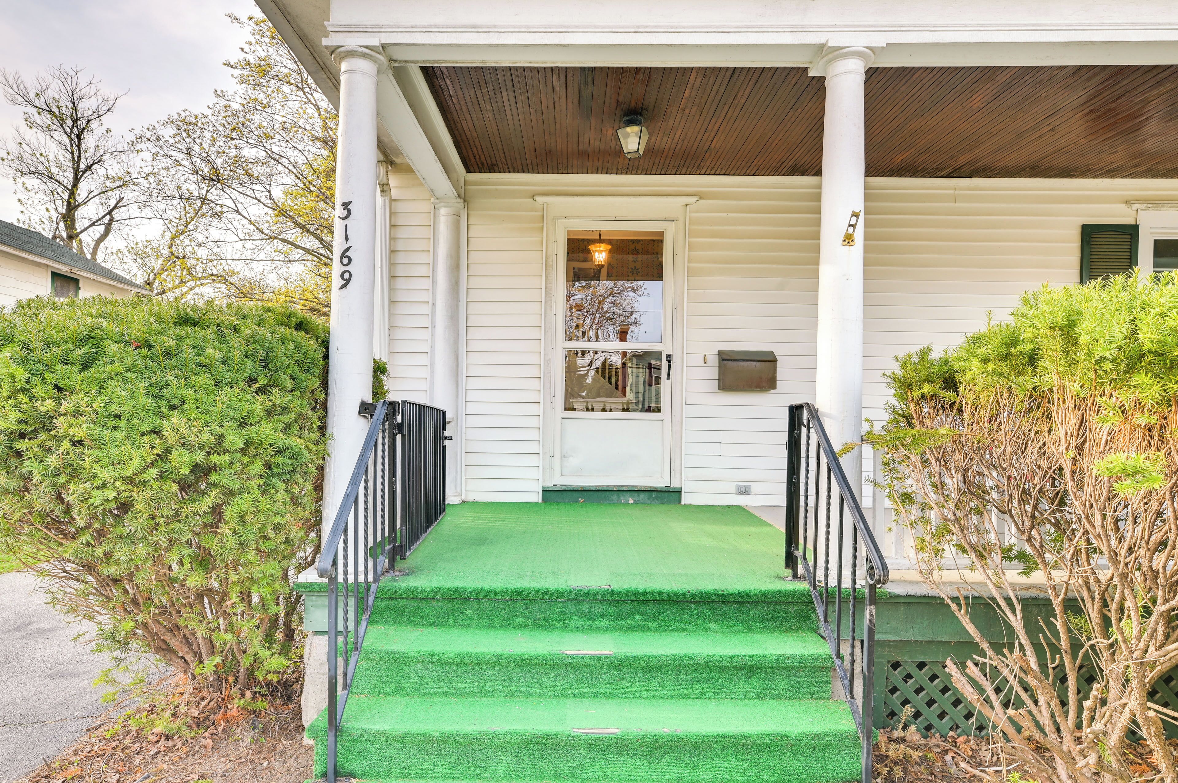 A white building with a green lawn and steps leading to a door.