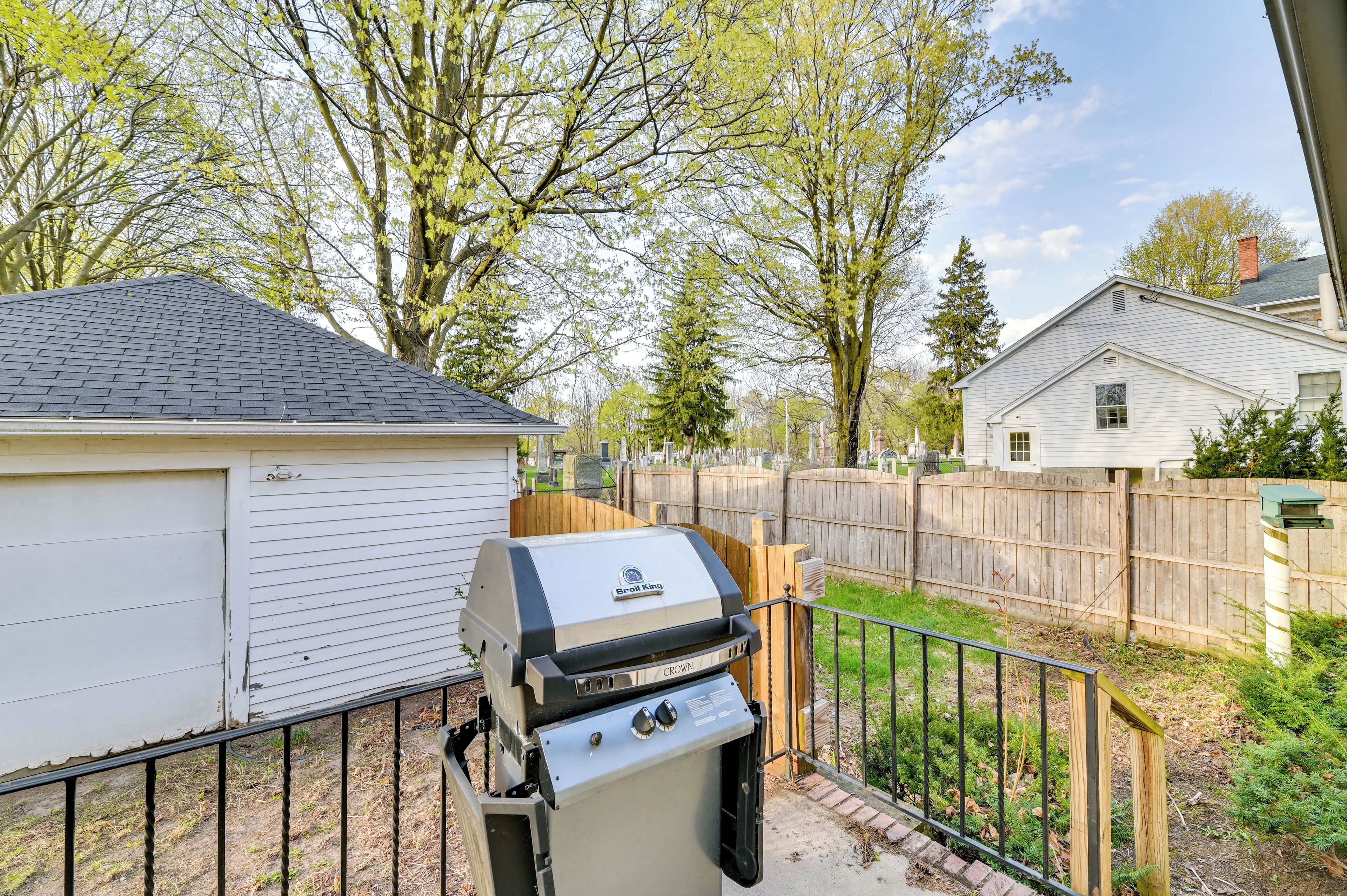 A backyard with a grill, a shed, and a wooden fence.