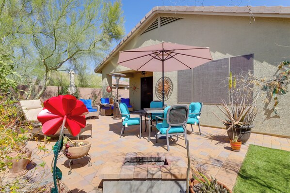Une terrasse avec des meubles d’extérieur, un grand parasol et des plantes en pot.
