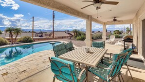 Une terrasse couverte avec une piscine, du mobilier d’extérieur et une vue sur le paysage environnant.