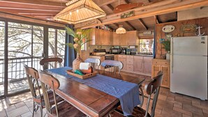 Een landelijke keuken met houten kastjes, een eettafel met stoelen, een koelkast en een hangende lamp.