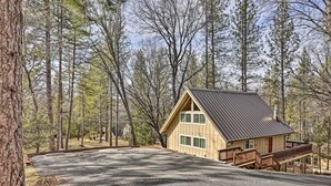 A cabin with a sloped roof, a front porch, and a driveway leading to a parking area surrounded by trees. - California Cabin w/ Lake Access: 28 Mi to Yosemite (Groveland)